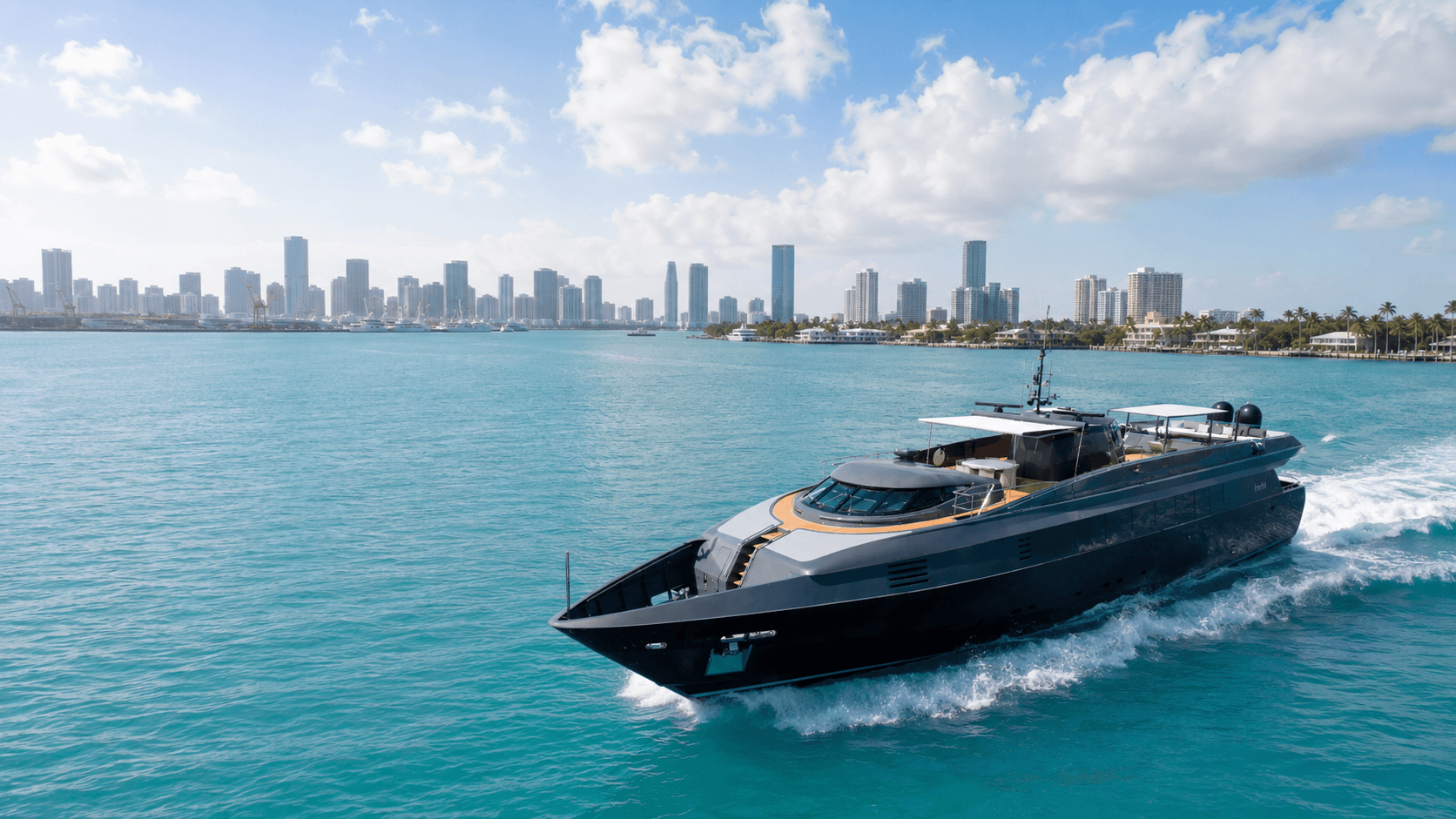 A sleek dark yacht speeds through turquoise water with a city skyline and palm trees in the distance.