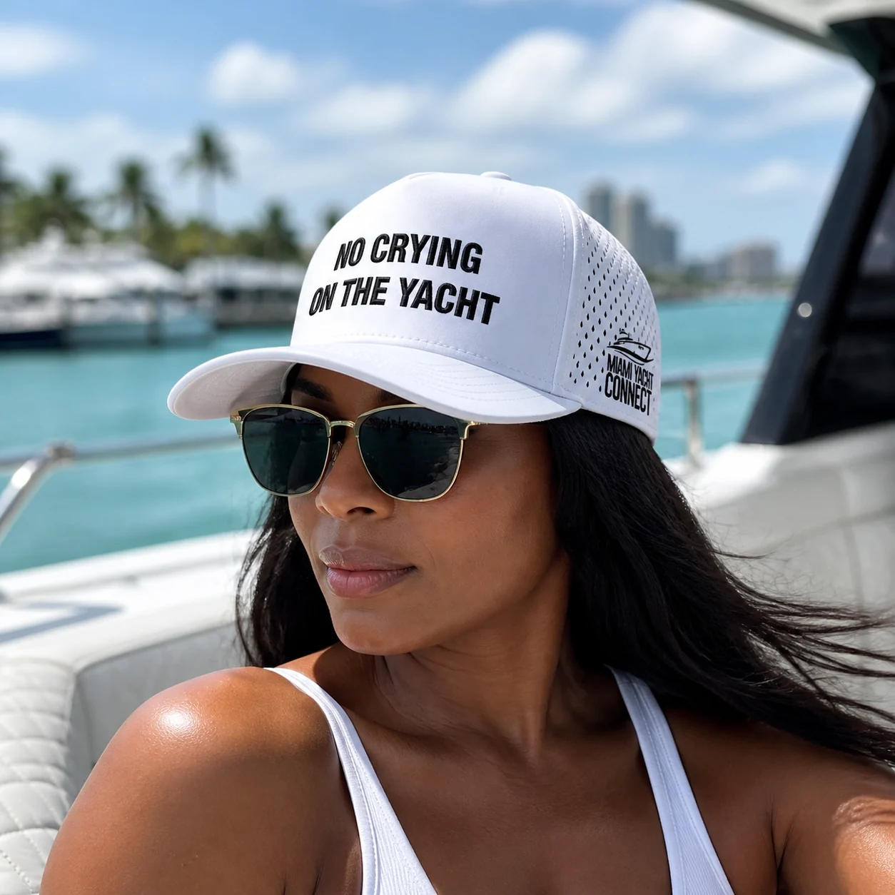 The white No Crying On The Yacht cap worn on a yacht in Miami